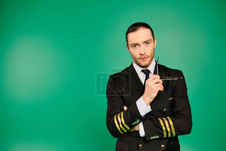 Handsome pilot in black uniform holding glasses.