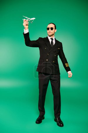 Elegante hombre de traje y gafas de sol, sosteniendo un avión modelo.