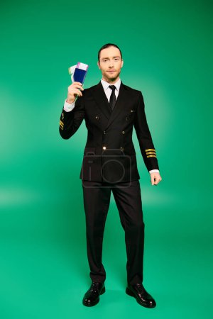 Photo for Handsome pilot in black suit holding a passport. - Royalty Free Image