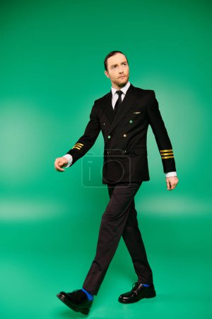 Stilvoller Mann in Anzug und Krawatte geht anmutig auf sattgrünem Hintergrund.