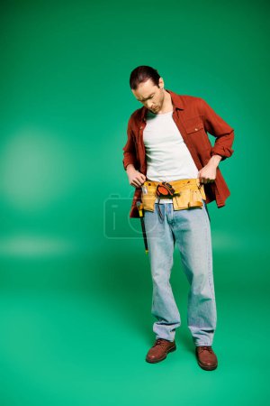 Un hombre de uniforme sostiene con confianza las herramientas contra un exuberante telón de fondo verde.
