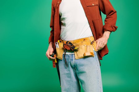 A man in a tool belt poses against a vibrant green backdrop.