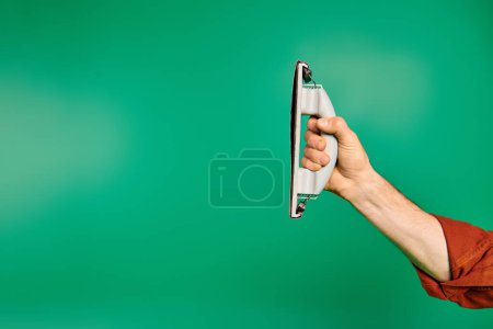Una mano enfocada, sosteniendo un pulidor sobre un vibrante fondo verde.