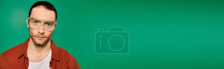 Photo for A man wearing glasses poses against a vivid green background. - Royalty Free Image