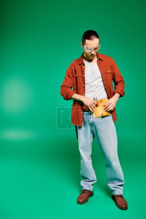 Téléchargez les photos : Un beau travailleur masculin en uniforme, posant avec des outils sur un fond vert vibrant. - en image libre de droit