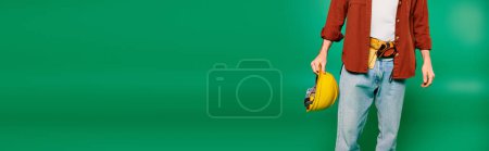 Photo for A worker in uniform holds a helmet in front of a green screen backdrop. - Royalty Free Image