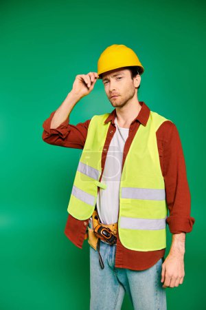 Ein Mann in Warnweste und Bollenhut posiert selbstbewusst mit Werkzeug vor grünem Hintergrund.
