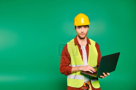 Photo for A man in a yellow safety vest holds a laptop. - Royalty Free Image