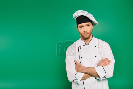 Handsome male chef in white uniform standing with arms crossed.