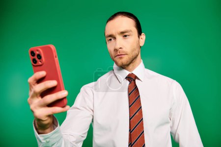 Businessman in white shirt and tie confidently uses a cell phone.