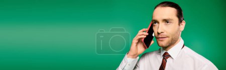 Photo for Handsome businessman in tie talking on cell phone against green backdrop. - Royalty Free Image