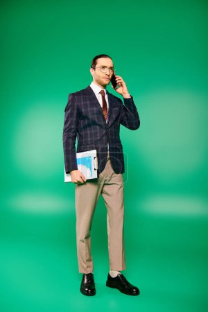 A handsome businessman in a chic suit talking on a cell phone against a green backdrop.