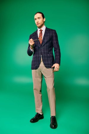 Un hombre de negocios guapo con un traje elegante y corbata posa con confianza sobre un vibrante fondo verde.