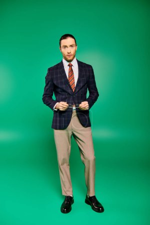 Handsome businessman poses in a chic suit on a green backdrop.