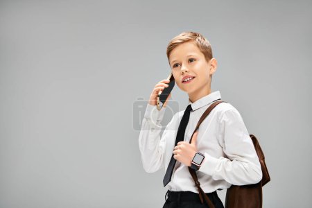 A young boy in elegant attire holds a cell phone to his ear.