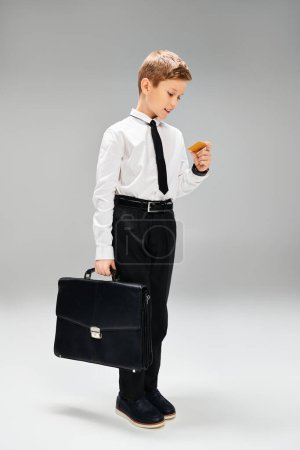 Niño preescolar con traje y corbata, sosteniendo con confianza un maletín.