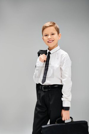 Un jeune garçon en chemise blanche et cravate tient une mallette.