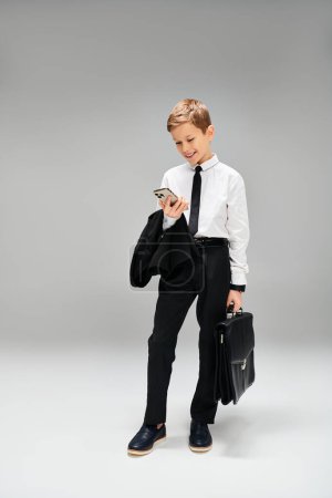 Preadolescent boy in suit and tie holding a briefcase.