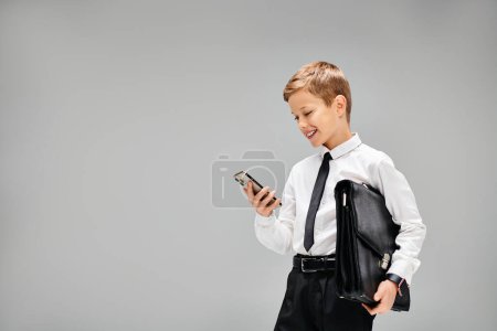 Liebenswerter frühpubertärer Junge in Hemd und Krawatte mit Handy.