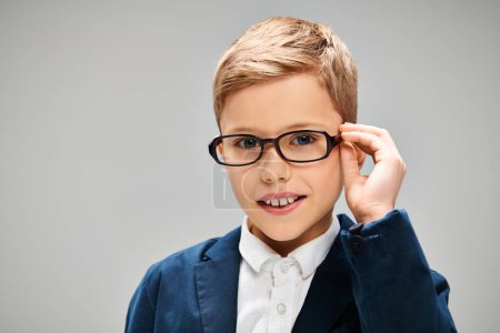 A little preadolescent boy in glasses and a suit, exuding intelligence and elegance.