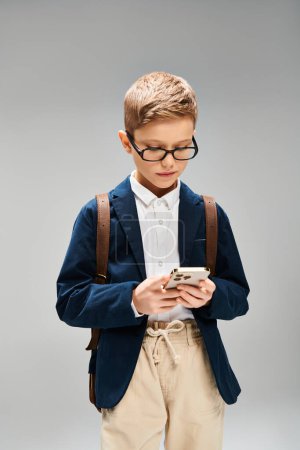 A preadolescent boy in blue jacket and glasses looks studious.