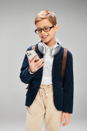 Un niño preadolescente con estilo en traje elegante, usando auriculares y sosteniendo un teléfono celular.