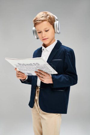 Niño en traje elegante, auriculares puestos, lee el periódico.