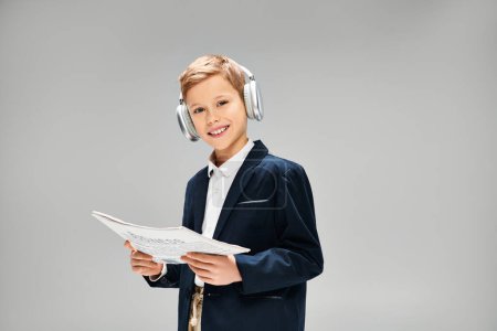 Young boy in elegant attire wearing headphones, holding paper.