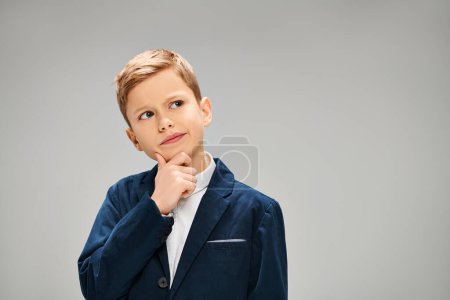 Photo for A preadolescent boy in a stylish blue suit poses for the camera against a gray backdrop. - Royalty Free Image