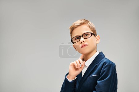 Hombre joven en gafas y chaqueta azul sobre fondo gris.