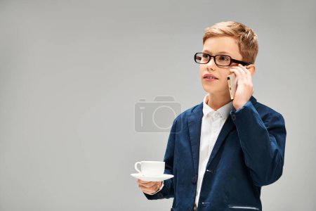 Preadolescent boy in suit and glasses talking on cell phone.