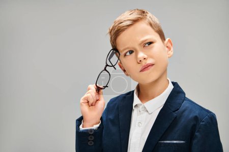 Young boy in formal attire examining glasses closely.