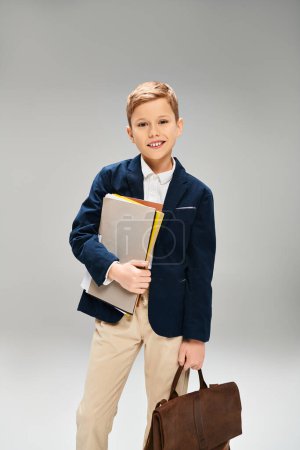 Niño vestido con elegante atuendo sosteniendo un libro y un maletín.
