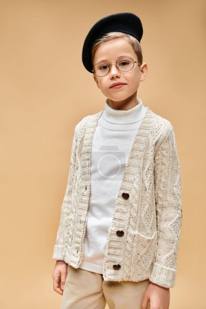 Young boy with glasses and hat, emulating a film director, on a beige backdrop.