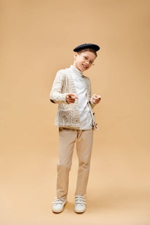 A cute preadolescent boy dressed as a film director on a beige backdrop.
