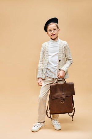 Preadolescent boy dressed as film director holds a brown briefcase.