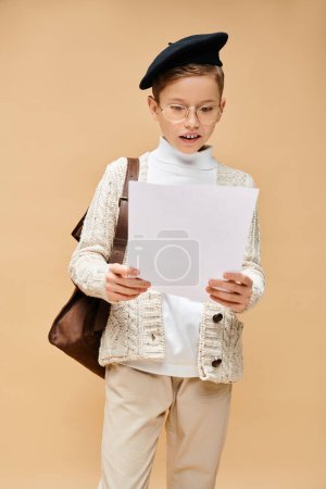 Netter vorpubertärer Junge, der als Filmregisseur verkleidet ist und ein Blatt Papier in der Hand hält.