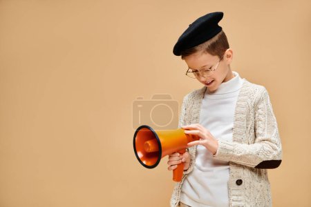 Un jeune garçon habillé en réalisateur tenant en toute confiance un mégaphone jaune et noir.