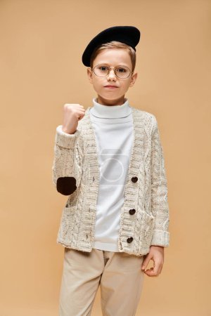 Ein kleiner Junge im Pullover mit Brille träumt und schafft vor beigem Hintergrund.