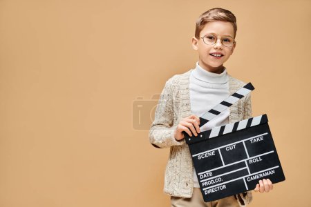 Vorpubertärer Junge posiert als Filmregisseur mit Filmtafel.