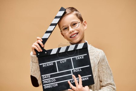 A young boy disguised as a film director hides behind a clapper board.