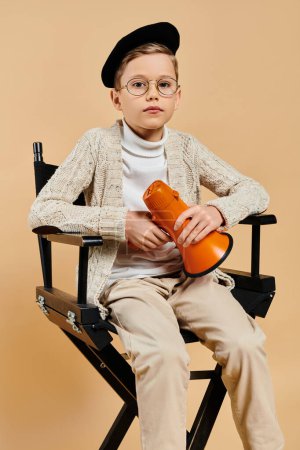 A preadolescent boy, dressed as a film director, sitting in a chair holding a megaphone.