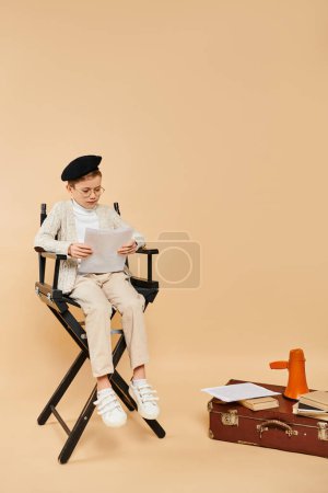 Téléchargez les photos : Garçon assis, profondément absorbé dans la lecture d'un morceau de papier. - en image libre de droit