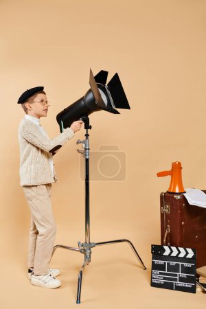 Photo for Preadolescent boy stands confidently next to camera and tripod. - Royalty Free Image
