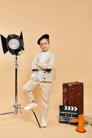 A cute preadolescent boy dressed as a film director, standing confidently in front of a camera.