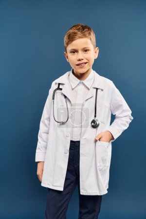 Preadolescent boy in white coat and stethoscope on blue backdrop.
