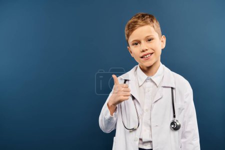 Ein niedlicher vorpubertärer Junge in weißem Mantel hält ein Stethoskop vor blauem Hintergrund.