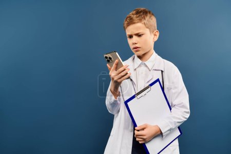 A young boy, holding a clipboard and a cell phone.