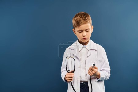 Téléchargez les photos : Un jeune garçon habillé en médecin, tenant un stéthoscope. - en image libre de droit