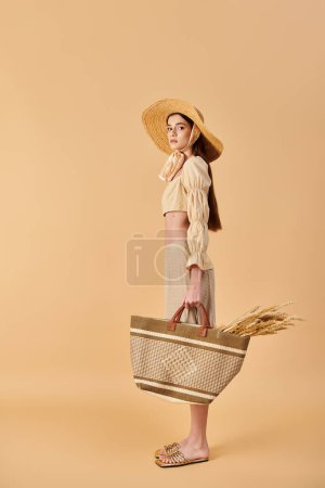 Téléchargez les photos : Une jeune femme aux longs cheveux bruns pose en tenue d'été, portant un chapeau de paille et tenant un panier. - en image libre de droit
